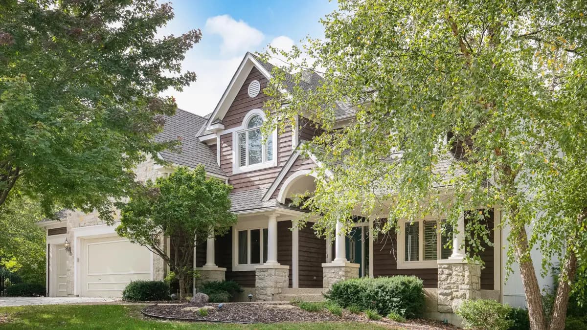 Contemporary two-story home exterior with stone porch columns and dark siding, Kansas City metro