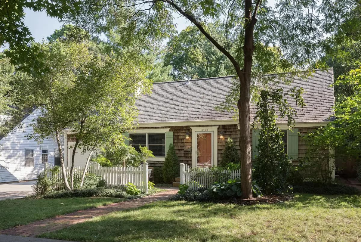 Cedar-shake cottage with white picket fence and brick walkway, Kansas City area listing