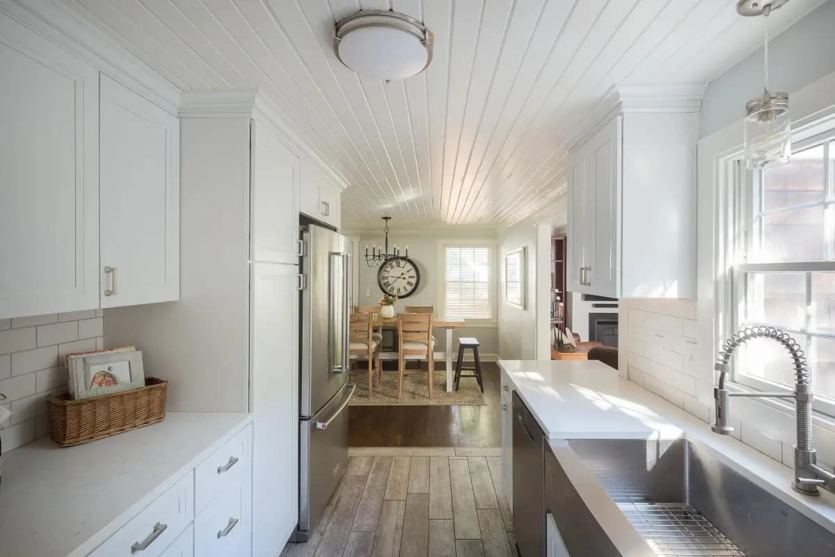 Bright white kitchen with farmhouse sink opening to dining room, Kansas City listing photography