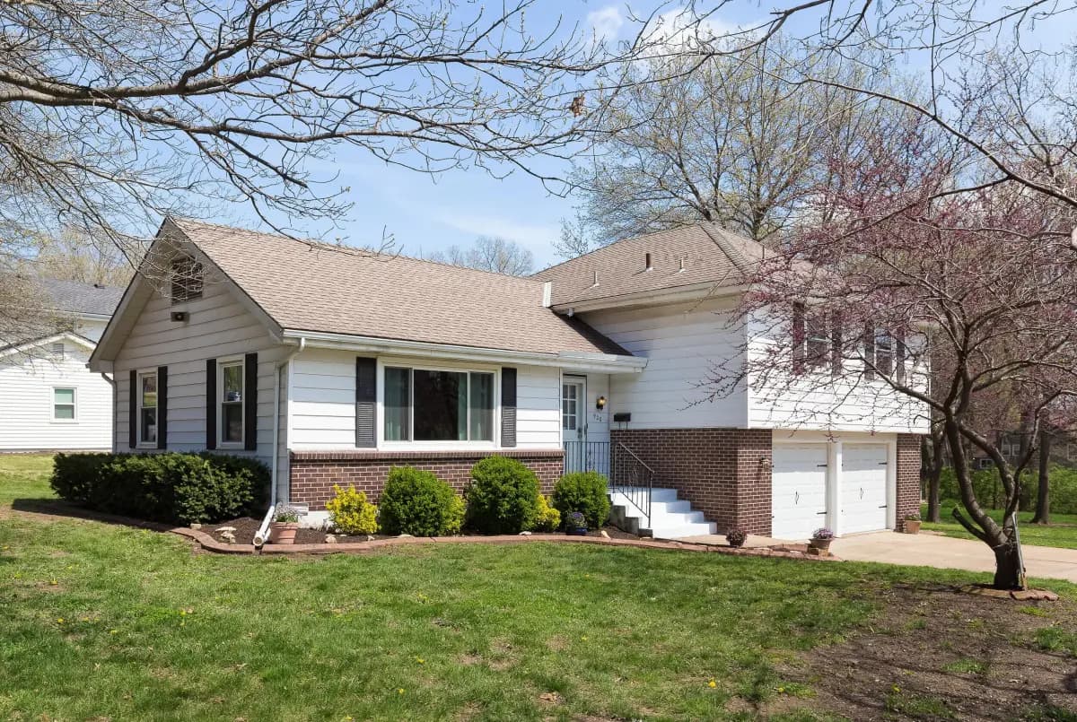 Split-level brick and white siding home exterior on a sunny day, KC metro