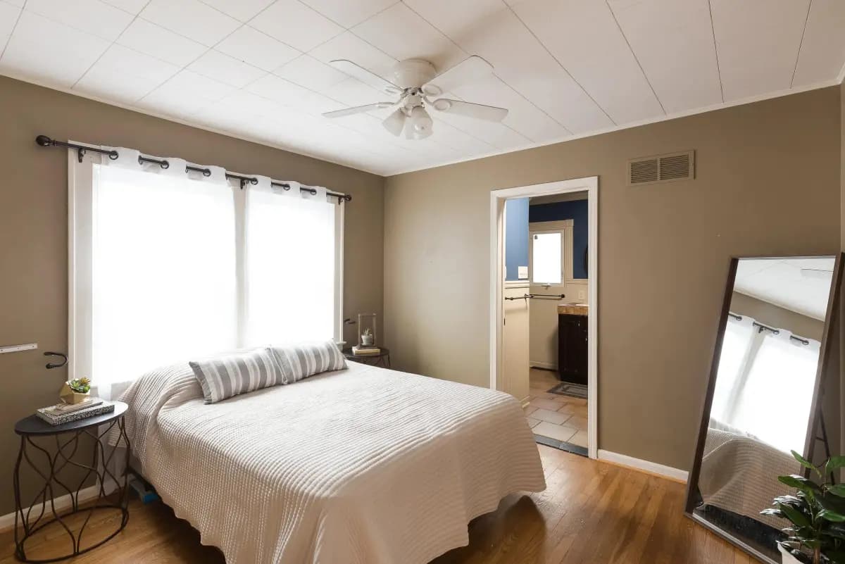 Sunlit bedroom with hardwood floors and ensuite doorway, Kansas City real estate photo