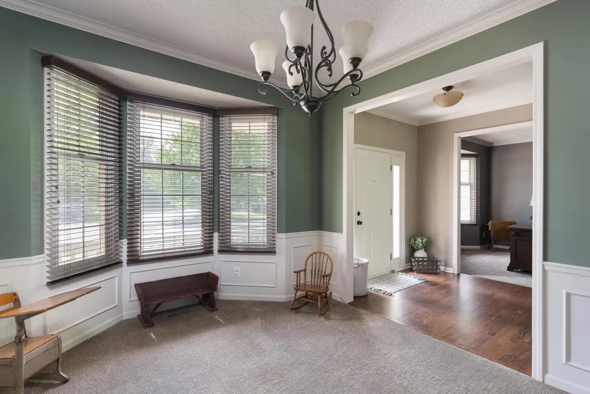 Sage green living room with bay window and wainscoting, Kansas City home
