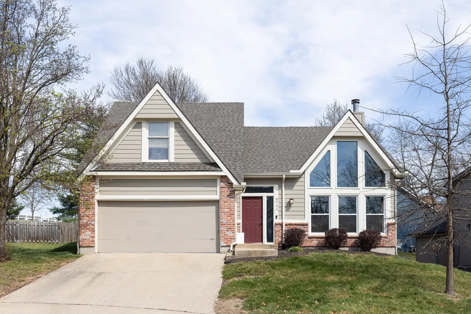 Craftsman home with a gabled porch and stone accents, Kansas City metro listing